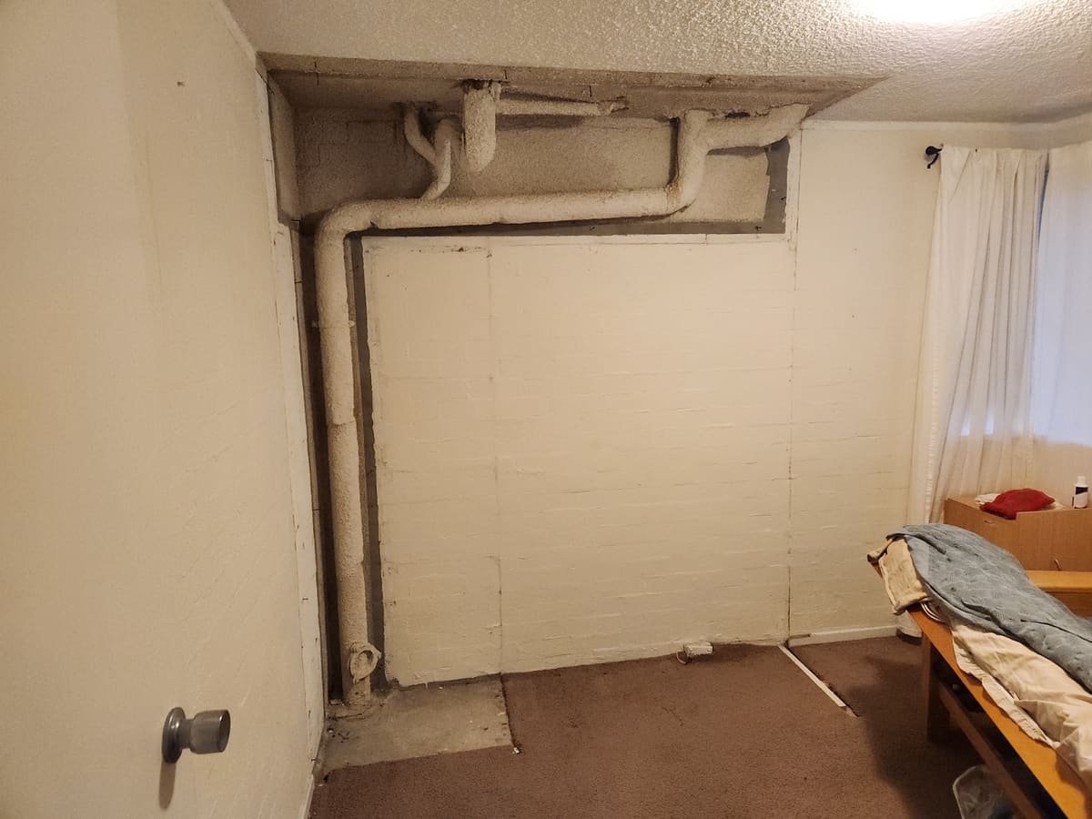 Built-in wardrobe over exposed pipework before